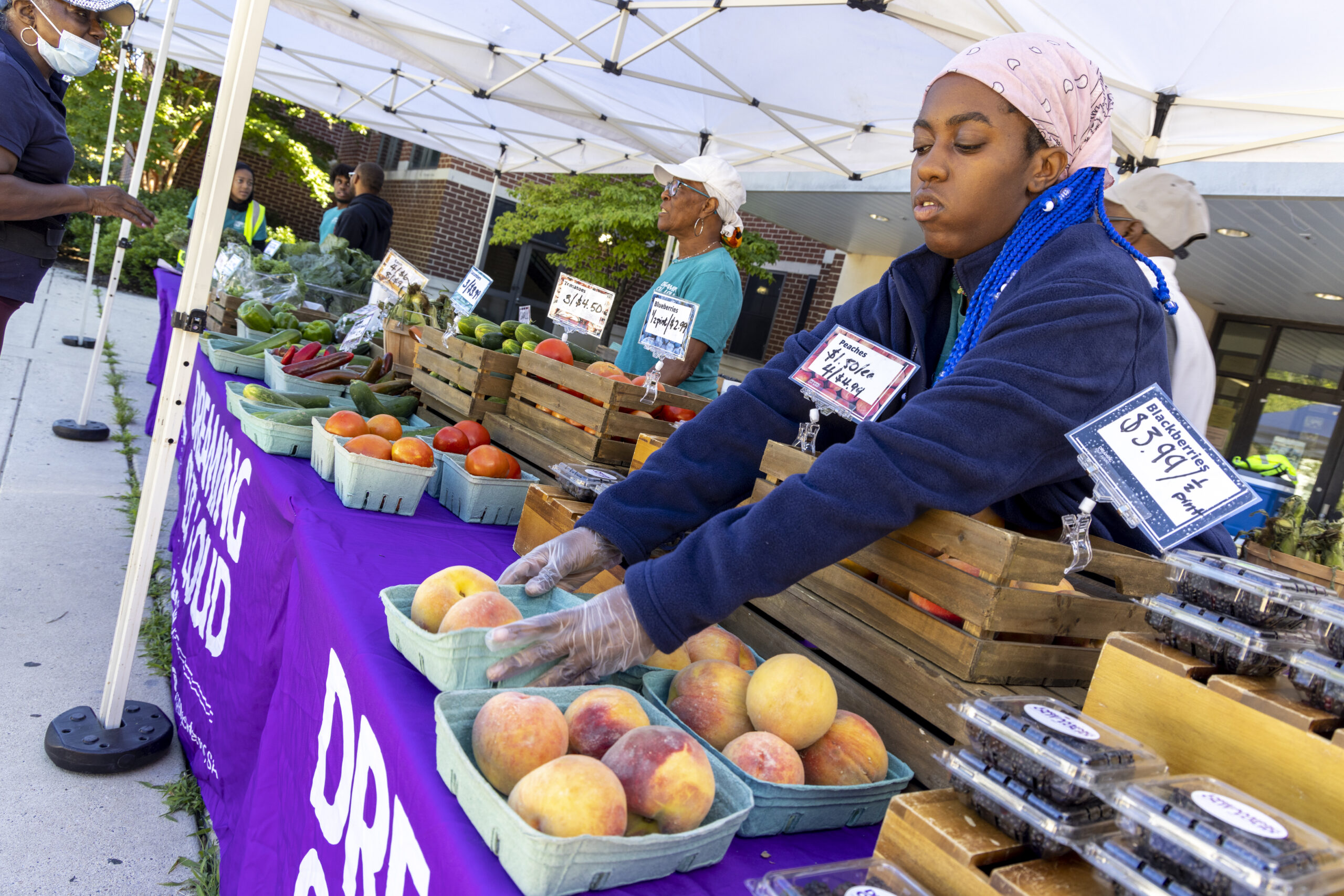 Person arranging fruit on a table at a farmers market