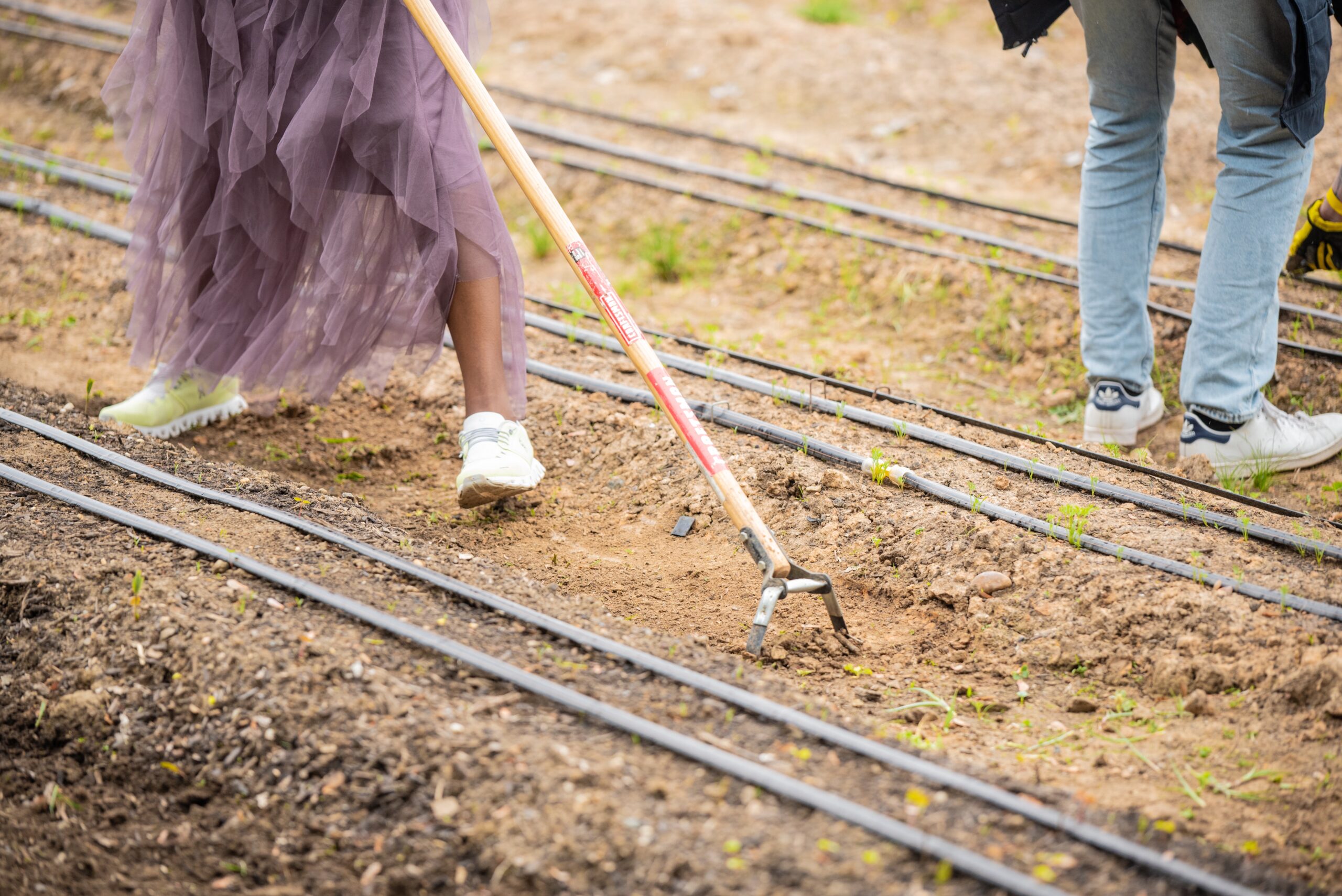 close-up of person's skirt and foot while they use farming equipment to till soil