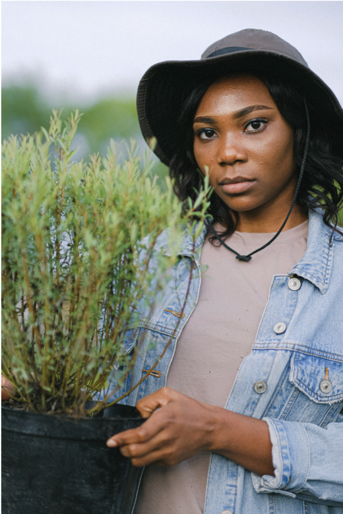 black female farmer holding a plant