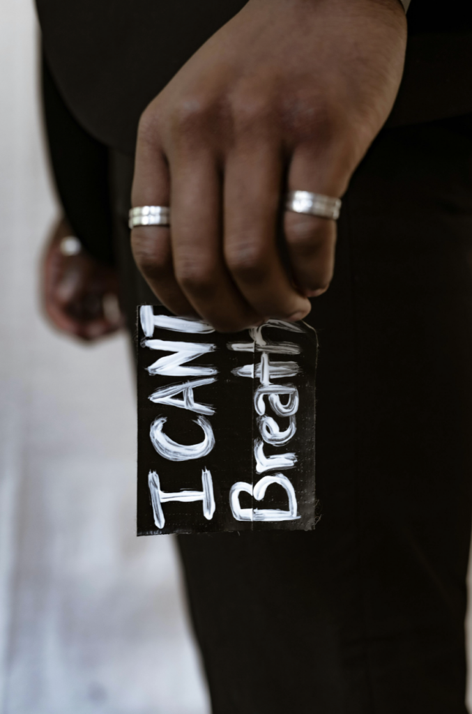 hand of a black person holding a sign that reads "I can't breathe"