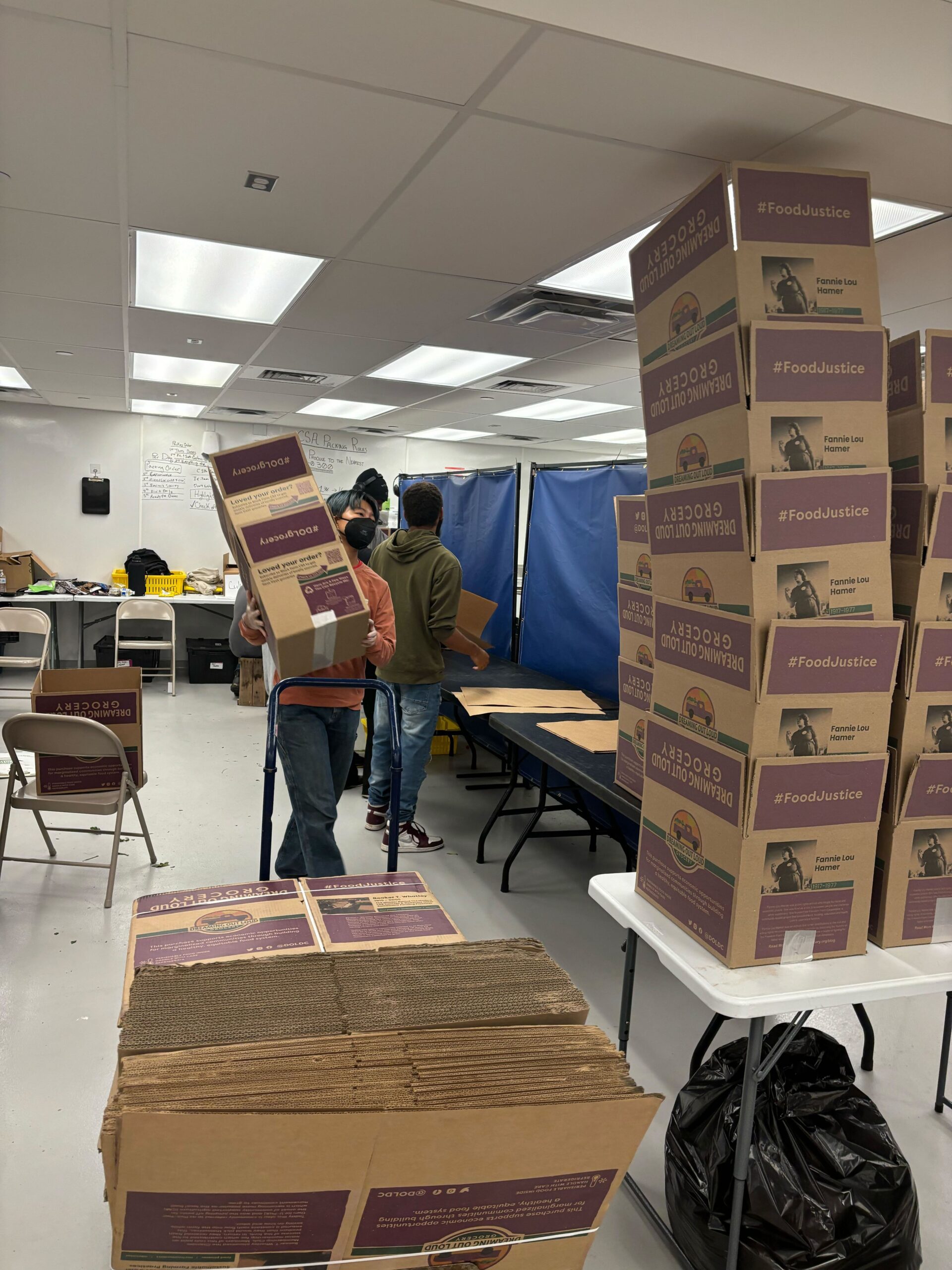People packing and carrying boxes inside of a warehouse