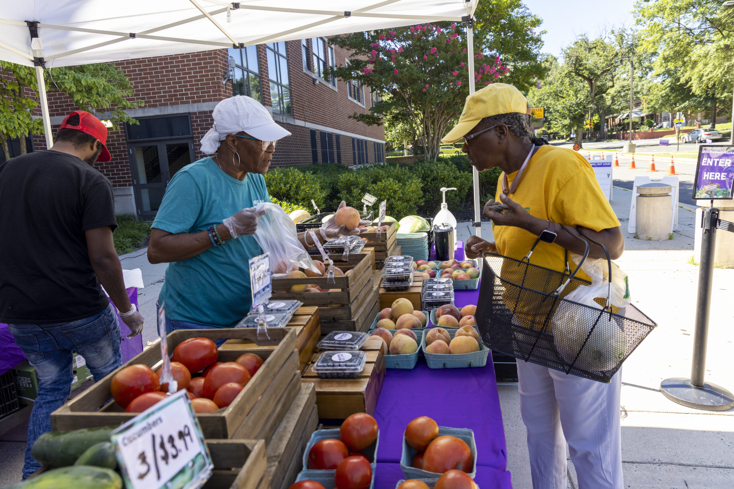 woman buying produce from a staff member at an outdoor market